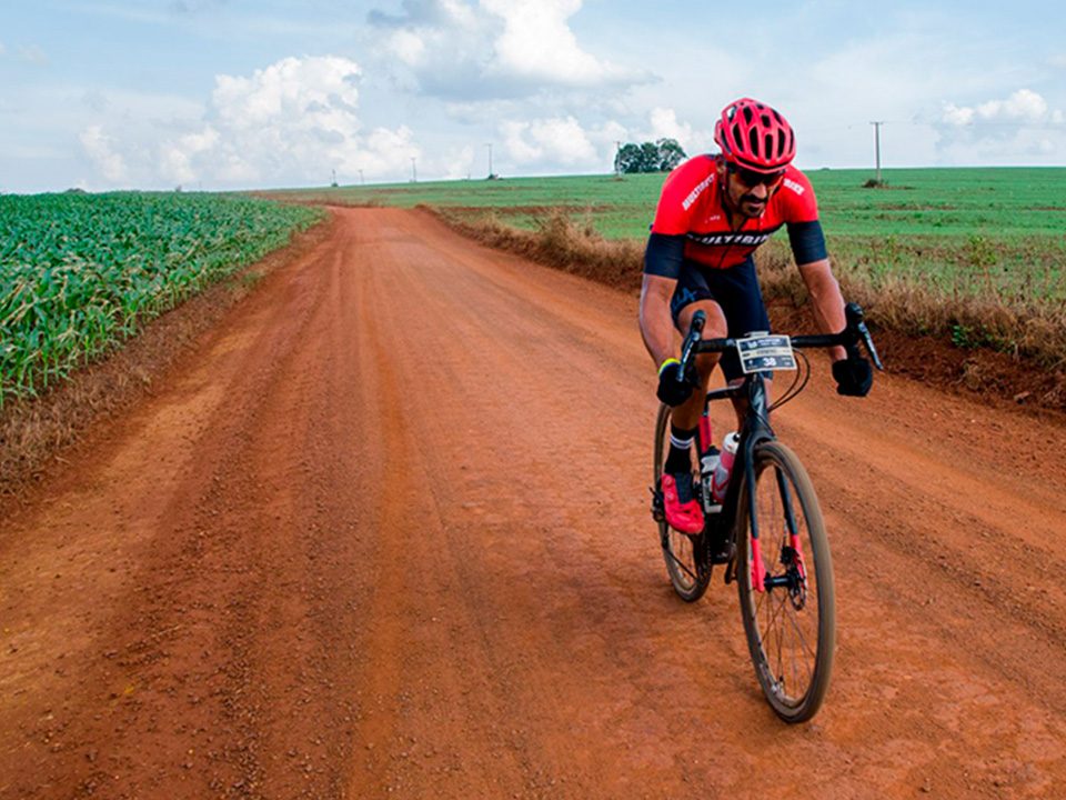 cilclista pedalando em rua de terra com uma bicicleta gravel